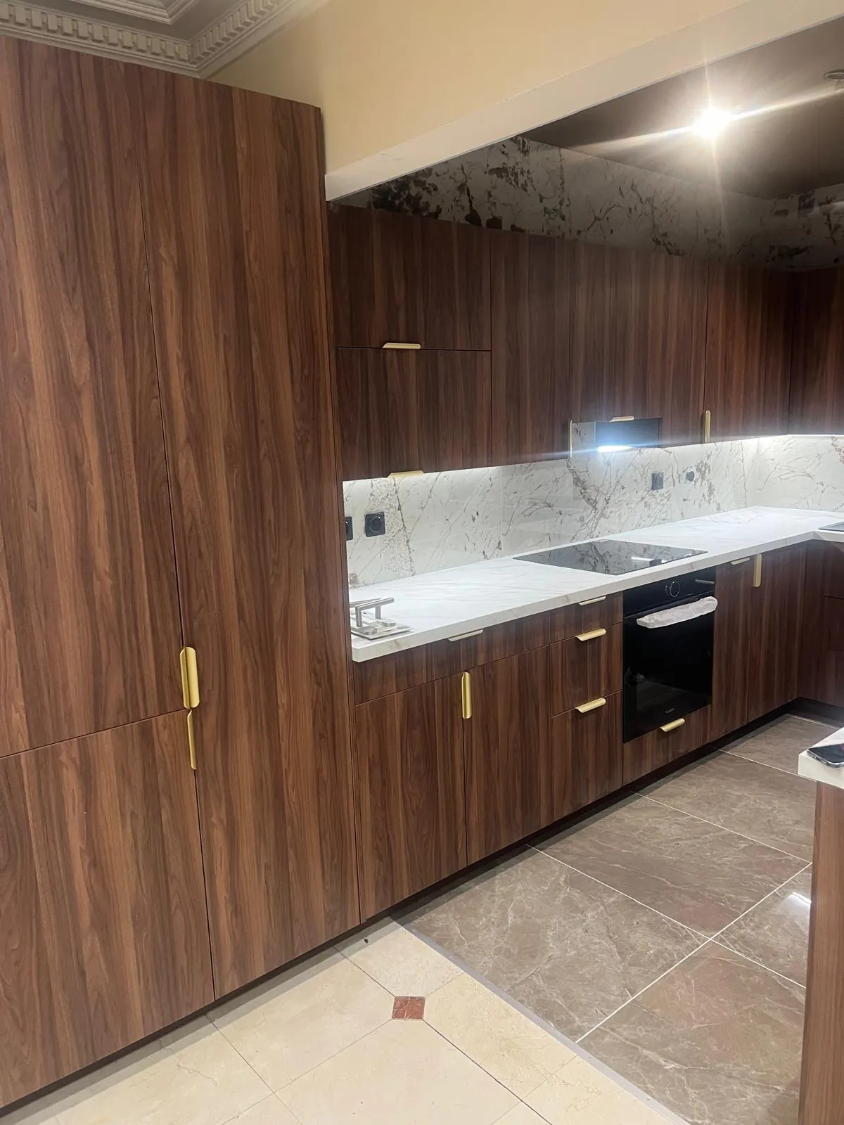 Cuisine sur mesure en noyer massif avec poignées laiton et plan de travail marbre — fabrication Atelier M Team